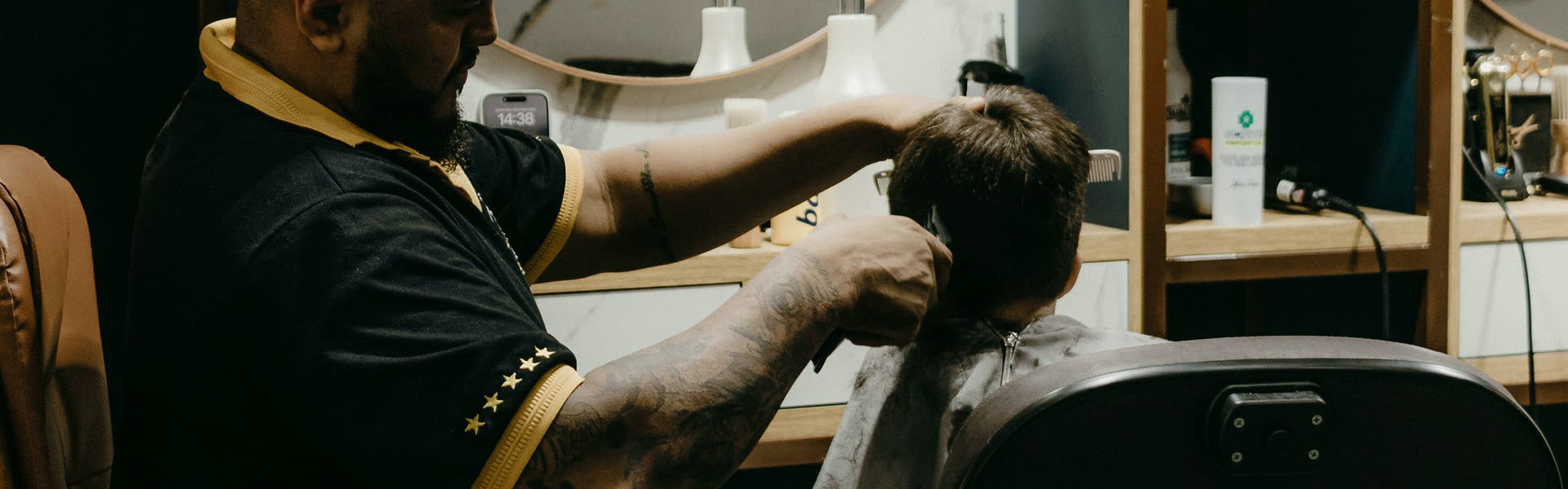 Barberare som klipper en kunds nacke i salongens varma ljus