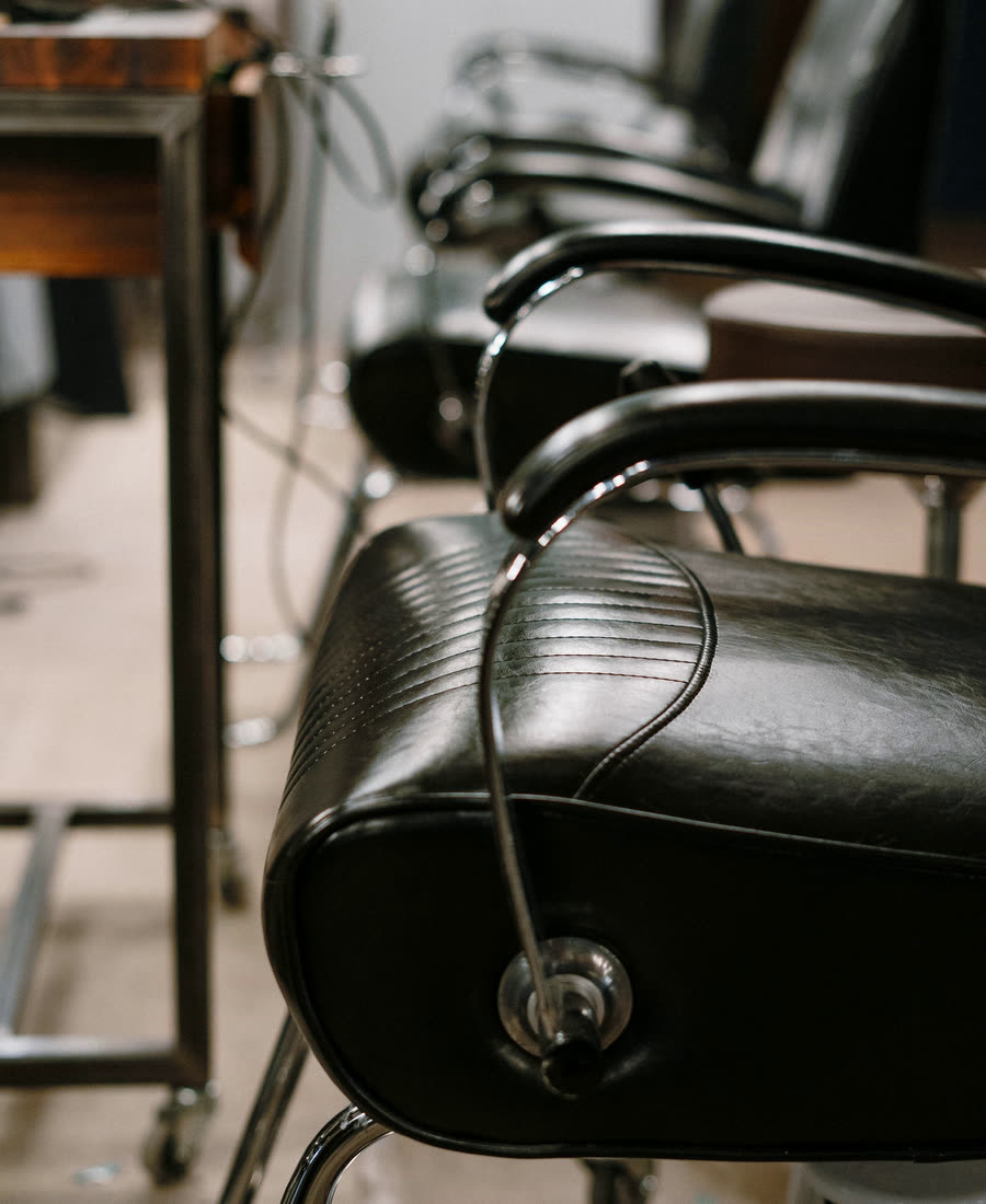 Tomma barberarstolar i rad längs salongens vägg
